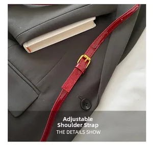 Detail of red patent leather strap with gold buckle on modern shoulder bag