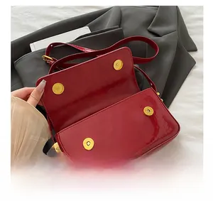 Detail showing four gold magnetic snaps on red patent leather handbag flap with metal hardware
