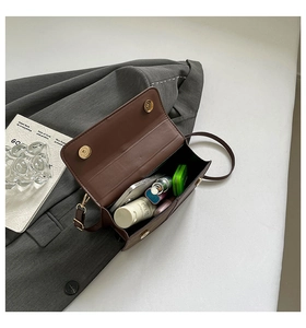 Internal storage detail of a dark brown leather crossbody bag with items inside