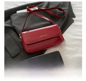 Detail of red patent leather shoulder bag showing glossy texture and gold brand logo