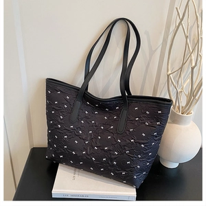 Detalle del bolso tote plisado negro con lazos blancos y correa larga para el hombro