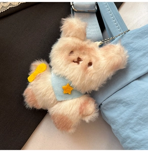 Close-up of a cute plush dog charm with a blue scarf on a minimalist shoulder bag