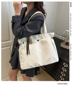 Close-up of white ruched tote bag with woven tassel detail and drawstring side feature