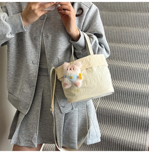 Detail of canvas tote bag with TOP RAH print and pink teddy bear charm accessory