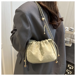 Detail of light green bucket bag with gold chain strap and elegant drawstring closure