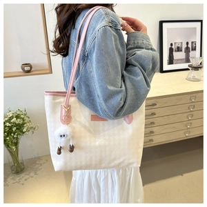 Dettaglio di una borsa tote grande con manici rosa e un grazioso ciondolo di peluche