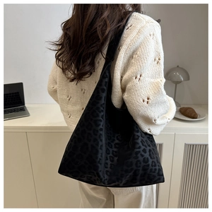 Détail d'un sac cabas noir à motif léopard porté par un mannequin dans un cadre intérieur doux
