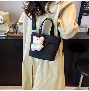 Détail du sac seau en nylon noir avec logo RAH TOP, breloque ours peluche et bandoulière large