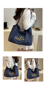 Detail van de grote denim shopper met levendig geel geborduurd Hello-scriptmotief