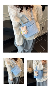 Détail du sac bandoulière bleu clair texturé avec un pendentif d'ours en peluche blanc