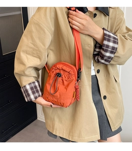 Detail einer orangen Umhängetasche mit Kordelzug, Stickerei und verstellbarem Gurt
