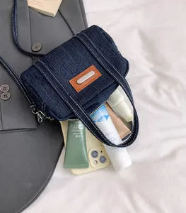 Detail of blue denim crossbody bag interior showing daily essentials on white fabric