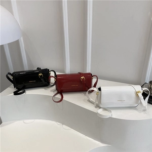 Minimalist patent leather crossbody bags in black, red, and white on a modern display