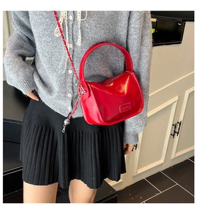 Close-up of red glossy PU leather shoulder bag with chain strap and Fashion label
