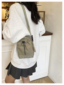 Détail du sac bandoulière kaki avec cordon de serrage, broderie et sangle en nylon