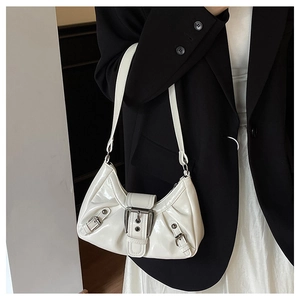 Close-up of cream pleated patent leather shoulder bag with decorative silver buckles