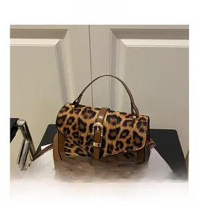 Close-up of leopard print handbag with brown leather trim and golden buckle detail