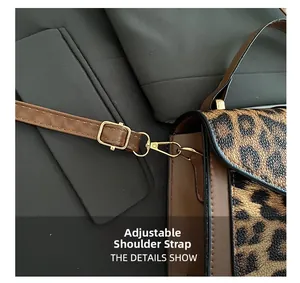 Detail of adjustable brown leather shoulder strap and golden metal hardware on leopard bag