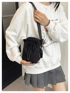 Detail of black nylon drawstring crossbody bag with embossed logo and adjustable strap