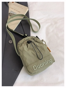 Détail du sac bandoulière en nylon vert olive avec cordon de serrage, broderie et étiquette
