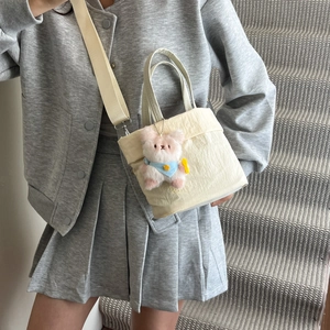 Sac à bandoulière minimaliste en toile beige avec large sangle et pendentif ours