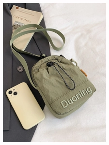 Détail du sac à bandoulière en nylon vert olive avec cordon de serrage et broderie
