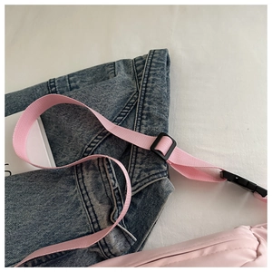 Close-up of pink casual crossbody bag with nylon strap and black plastic buckle detail