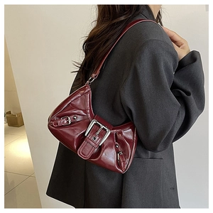 Detail of burgundy patent leather bag with silver buckle and pleated texture