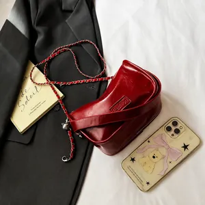 Detalle de bolso bandolera de cuero encerado rojo con cadena y colgante de plata