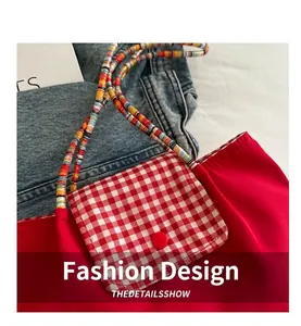 Detalle del bolso tote rojo de nailon con bolsillo de cuadros y correa trenzada