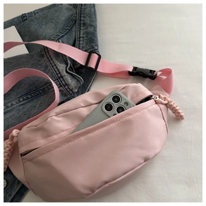 Pink nylon crossbody bag with front pocket showing smartphone for size reference