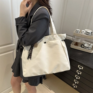 White pleated drawstring tote bag for women with tassel charm in minimalist indoor setting