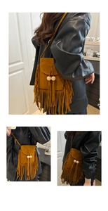 Detail of a brown suede crossbody bag featuring long fringes and decorative wooden beads