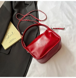 Dettaglio della borsa in pelle lucida rossa con tracolla a catena su sfondo bianco
