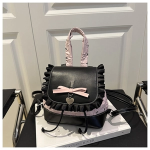 Detail von rosa Schleife und Herzanhänger auf schwarzem Rüschenrucksack für Frauen