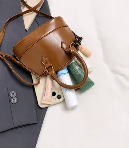Internal storage detail of brown leather shell bag showing smartphone and cosmetics