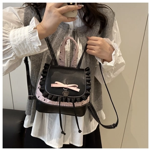 Close-up of pink and black mini backpack featuring a heart pendant and bow detail