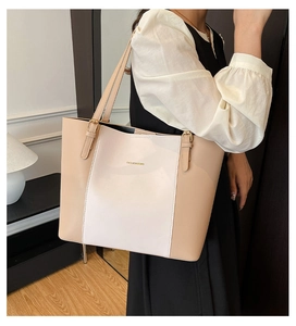 Model met een minimalistische beige en witte tote bag met gouden letterdetails