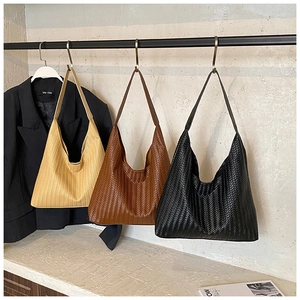Detalle de bolsos shopper tejidos en crema, caramelo y negro con correas anchas
