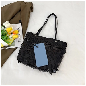 Top view of spacious black sequin tote bag with a phone for size reference on white cloth