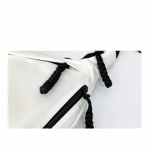 Detail van witte tas met zwarte hars rits en een geweven trekkoord voor de ritssluiting