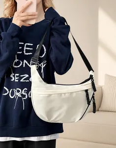 Detail van gebroken witte halve maan crossbodytas met zwart geweven trekkoord en verstelbare riem