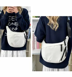 Detail van witte nylon crossbodytas met zwarte riem en geweven ritslipjes voor dames