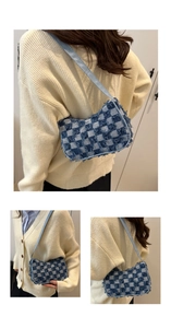 Detail view of checkerboard pattern denim underarm bag with frayed edges and slim straps