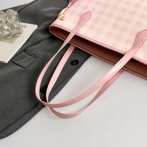 Close-up of pink checkered tote bag with leather handle and golden rivet detail
