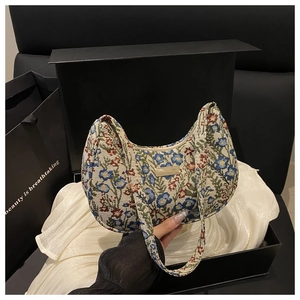 Detail of floral tapestry moon bag with gold plaque and luxury gift box packaging