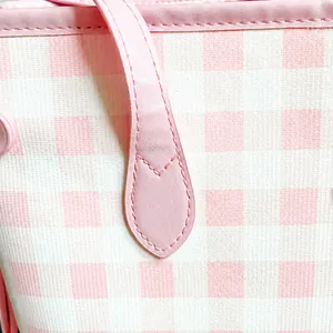 Macro detail of pink checkered fabric with high-precision stitching on leather handles