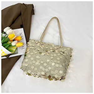 Detail of a chic gold sequin tote bag with sleek straps set on a minimalist white surface