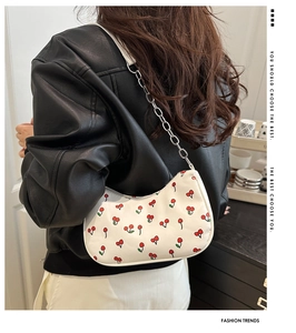 Détail de l'imprimé cerise et de la chaîne argentée sur le sac demi-lune blanc