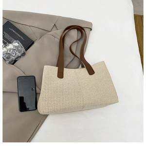 Dettaglio della borsa tote in tela beige con manici in pelle marrone e cuciture
